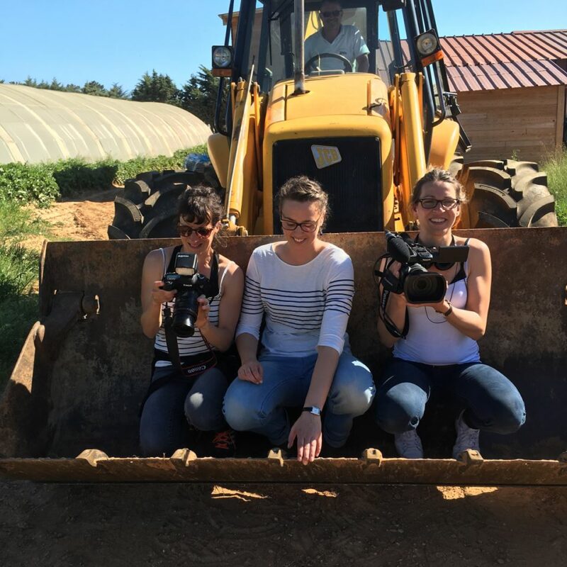 Équipe de consultantes en communication travaillant sur un projet de tournage dans un cadre agricole, illustrant leur engagement dans la création de contenu visuel et la stratégie de marque sur le terrain.