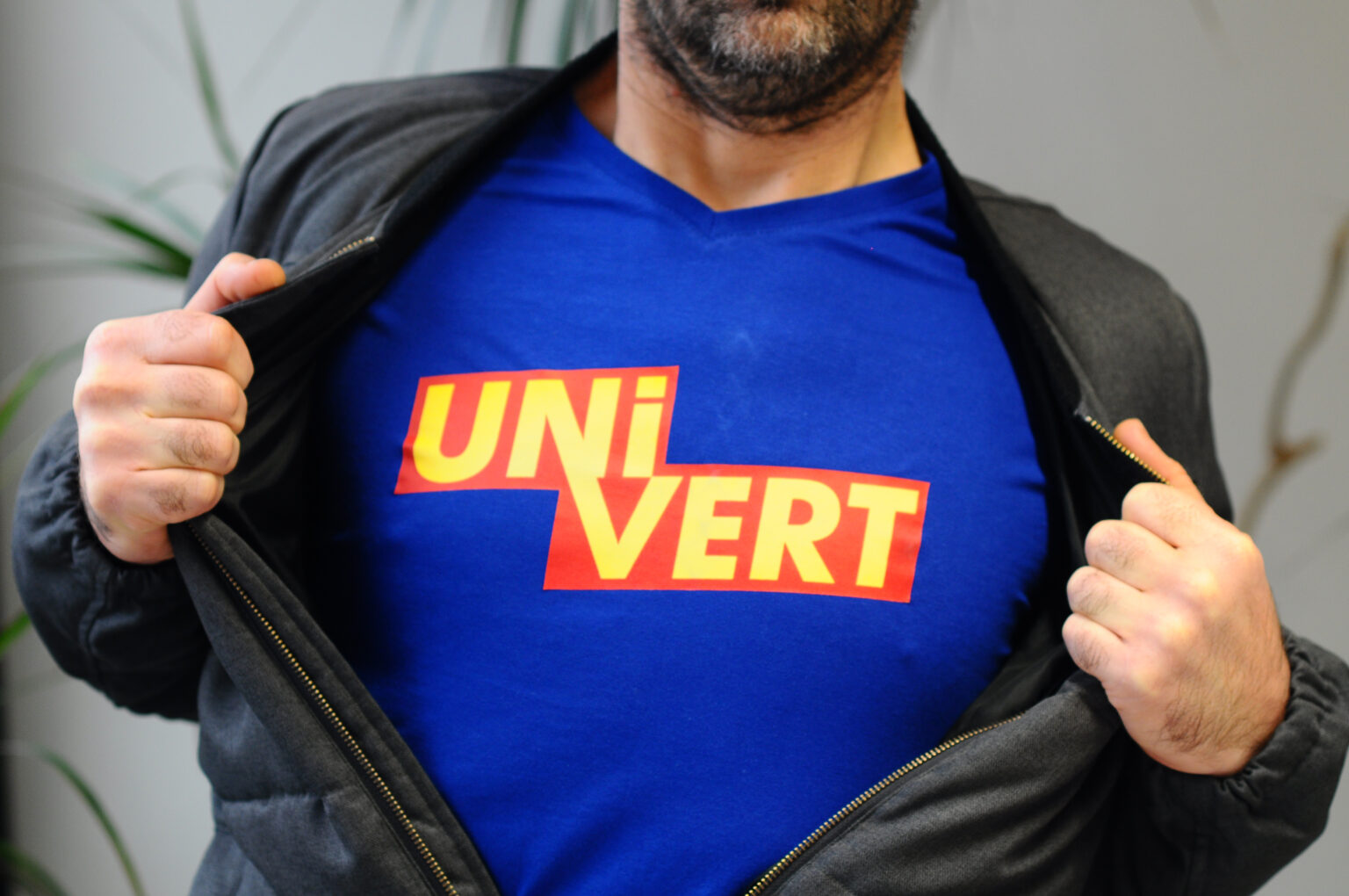 Personne portant un t-shirt bleu avec le logo "UNiVERT" en ouvrant sa veste